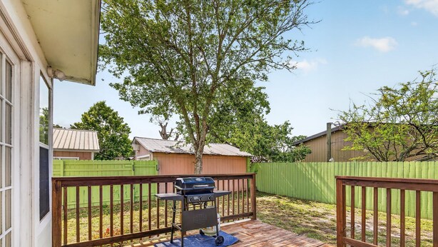 A wooden deck with a barbecue grill, a blue mat, and a green fence. - One More Cast Coastal House with Fenced Yard and Screened Porch near the Ocean (Fulton)