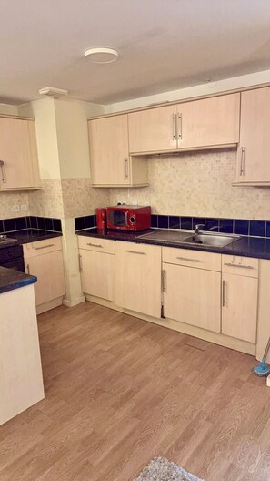 A kitchen with light-colored cabinets, a microwave, and a sink. - 2 Spacious Double Bedroom - Bradford City Center (Bradford)