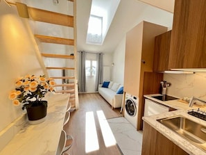 Un espacio habitable compacto con cocina, lavadora, sofá y escalera.
