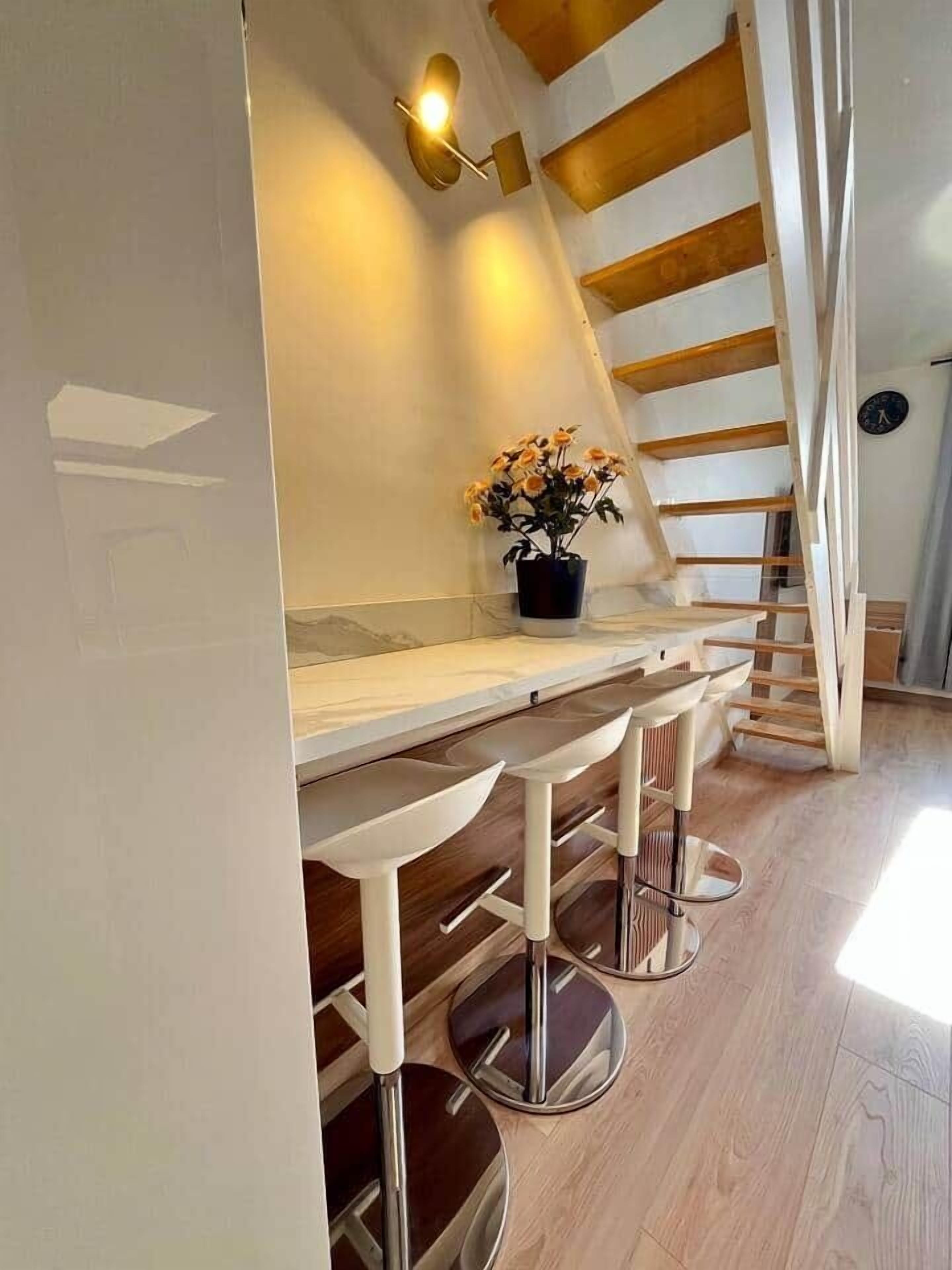 A kitchen with a wooden staircase, a countertop, and a potted plant.