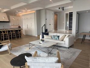 Un salon moderne avec un canapé, une table basse et des fauteuils. Il y a également un coin cuisine avec des placards et un espace repas.