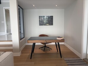 Un espace de bureau moderne avec un bureau en bois, une chaise et un tableau encadré accroché au mur.
