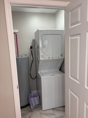 A laundry room with a front-loading washer and dryer, a utility sink, and a covered trash bin. - The Milk House No. 1- Farm life at its Best! (Bidwell)