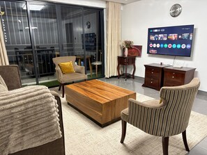 A modern living room with a flat-screen TV, a wooden coffee table, and two armchairs. - Spacious 3-bedroom family apartment in beautiful Nairobi with AC and gym (Nairobi)