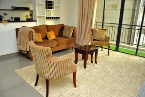 Un salon avec un canapé marron, deux fauteuils, une table basse et une grande fenêtre donnant sur un beau paysage.
