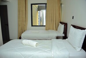 Ein Hotelzimmer mit zwei Betten, einem Fenster mit Vorhängen und einer Tür.