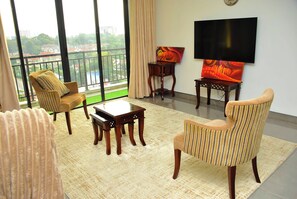 A living room with a sofa, armchair, coffee table, TV, and artwork on a stand. - Spacious 3-bedroom family apartment in beautiful Nairobi with AC and gym (Nairobi)
