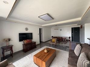 A modern living room with a flat-screen TV, wooden coffee table, sofa, and dining area. - Spacious 3-bedroom family apartment in beautiful Nairobi with AC and gym (Nairobi)