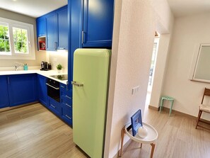 Eine moderne Küche mit blauen Schränken, einem grünen Kühlschrank und einem kleinen runden Tisch mit Bilderrahmen.