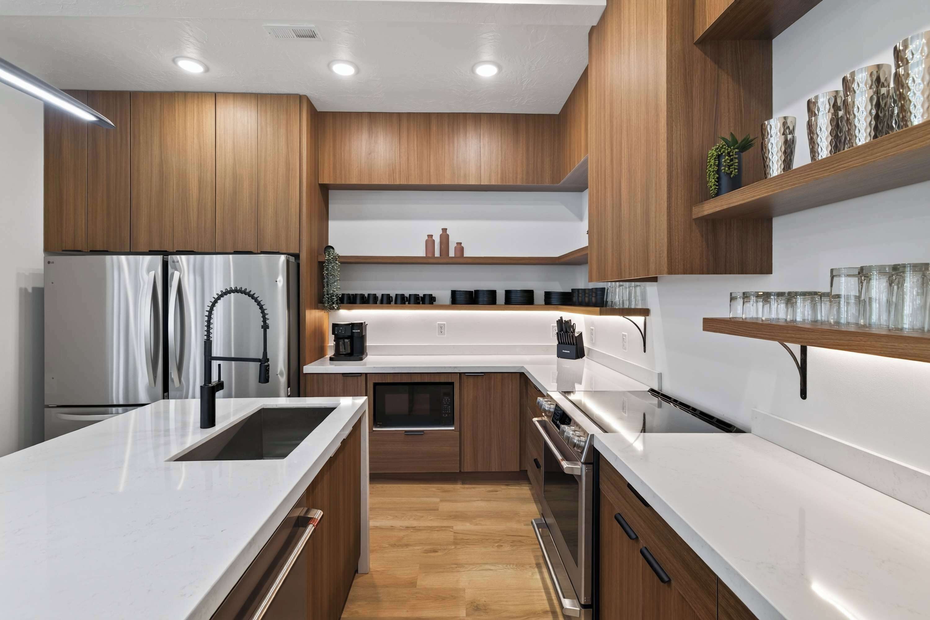A modern kitchen with wooden cabinets, stainless steel appliances, and a white countertop.