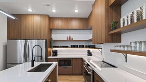 Une cuisine moderne avec des meubles en bois, des appareils en acier inoxydable et un plan de travail blanc.