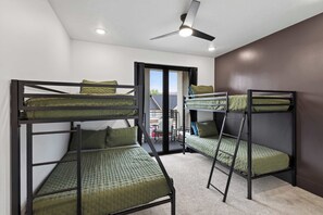 A dormitory room with bunk beds, a ceiling fan, and a view of the outside.
