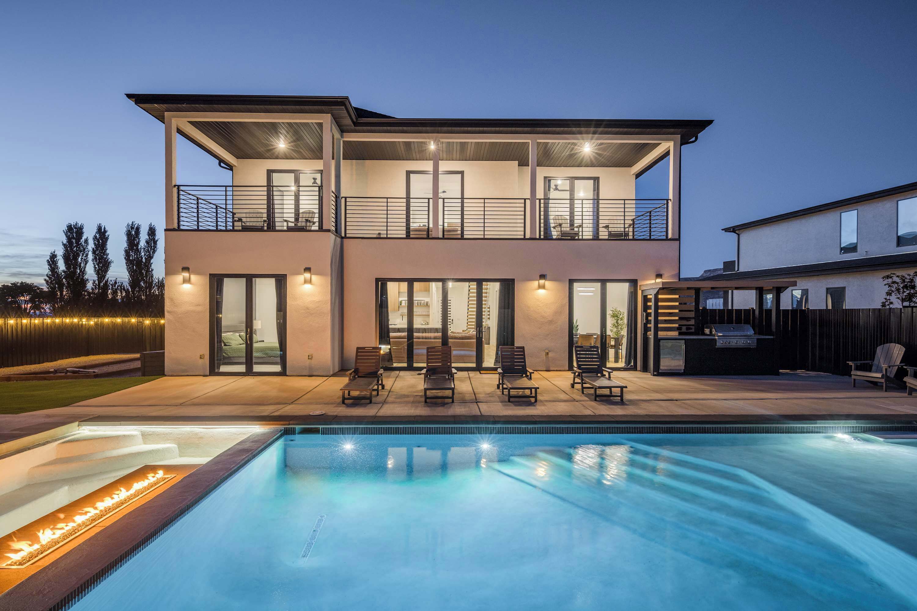 A two-story house with a swimming pool, outdoor seating, and a barbecue area.