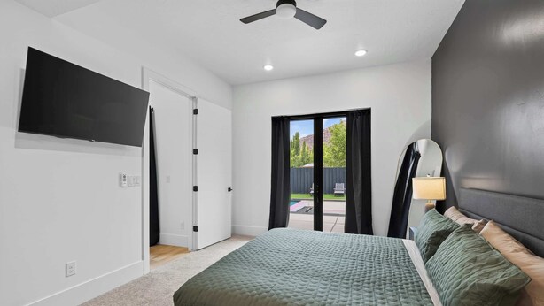 Une chambre à coucher avec un lit, un téléviseur, un ventilateur de plafond et une vue sur l’extérieur.