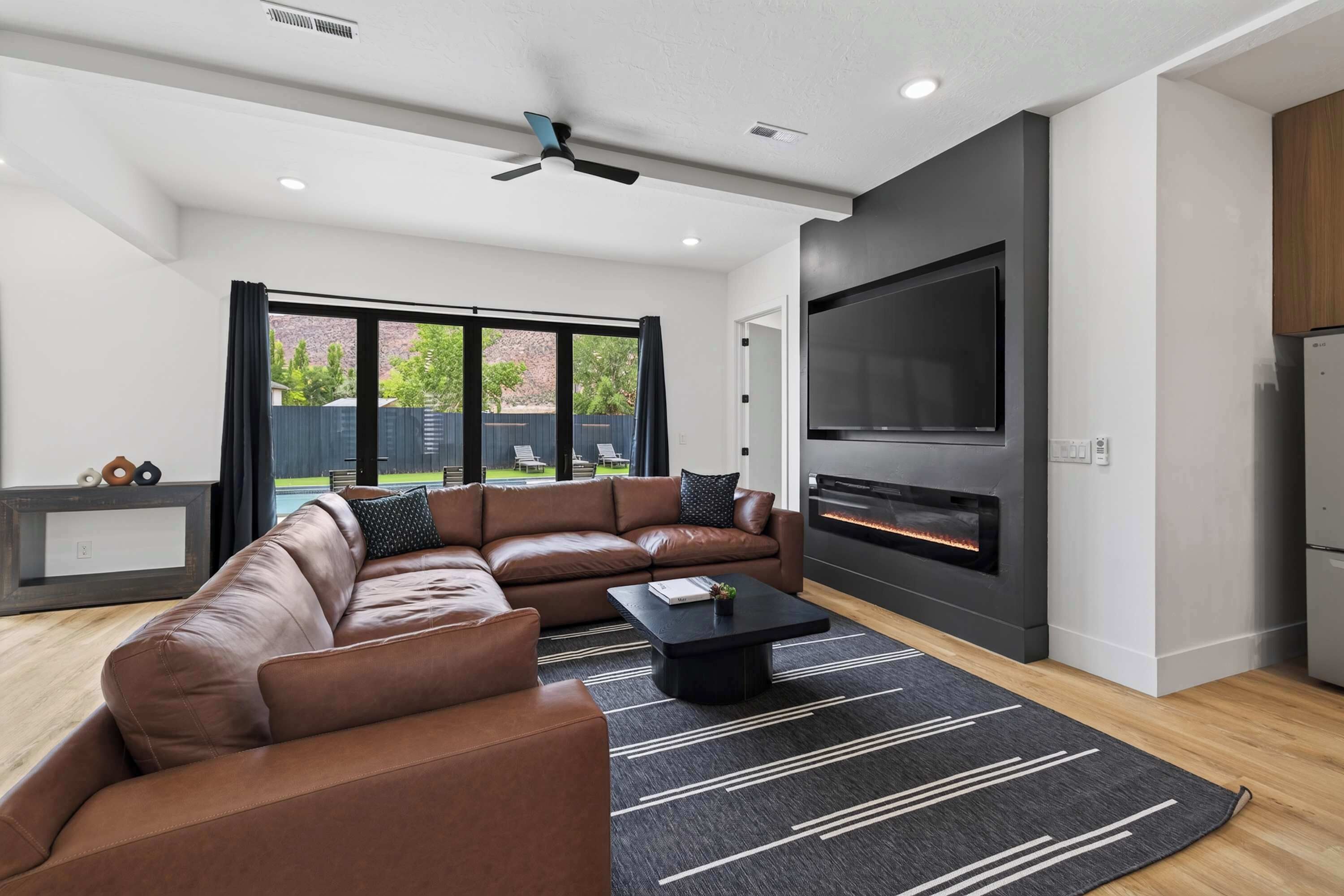 A modern living room with a sectional sofa, a flat-screen TV, and a fireplace.