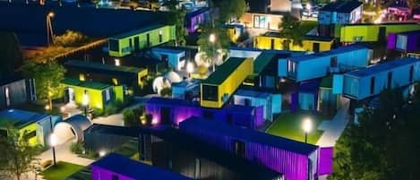 A residential area with multiple houses at night, illuminated by artificial lighting.