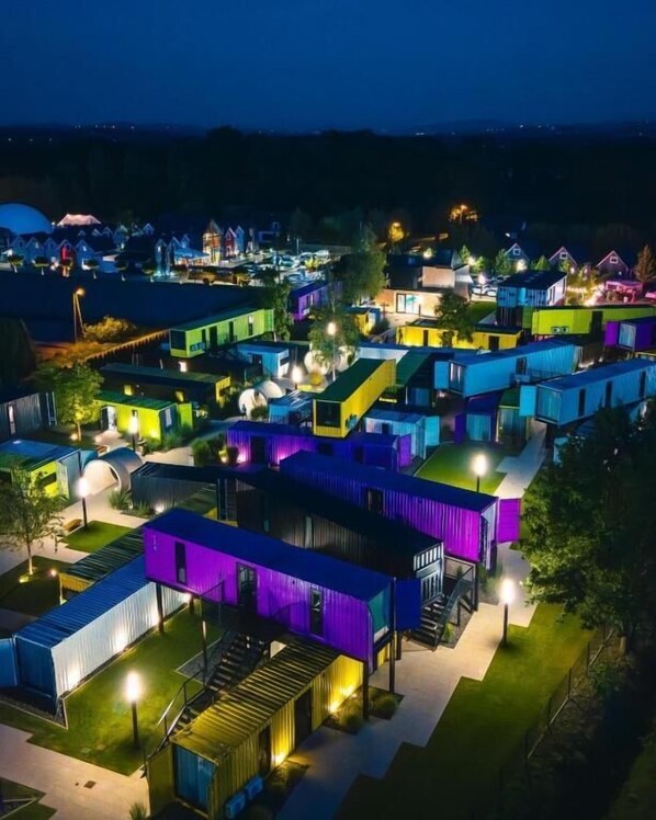 A residential area with multiple houses at night, illuminated by artificial lighting.