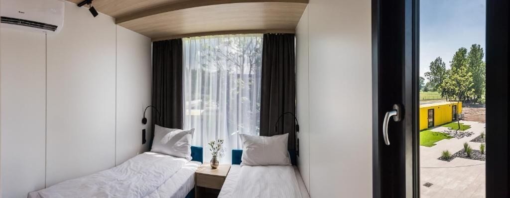 Una habitación con dos camas, una ventana con cortinas y vistas al exterior.