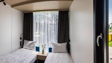 Una habitación con dos camas, una ventana con cortinas y vistas al exterior.