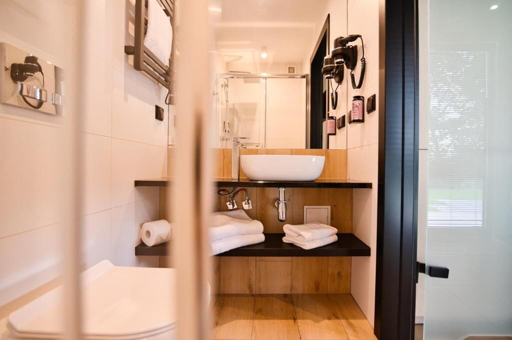 Une salle de bain moderne avec un lavabo blanc, un meuble-lavabo en bois et une cabine de douche en verre.
