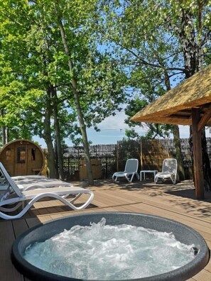 Un jacuzzi rodeado de sillas de descanso y una terraza de madera, con vistas al mar.