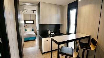Una kitchenette compacta con una pequeña zona de comedor, una cama y una ventana.