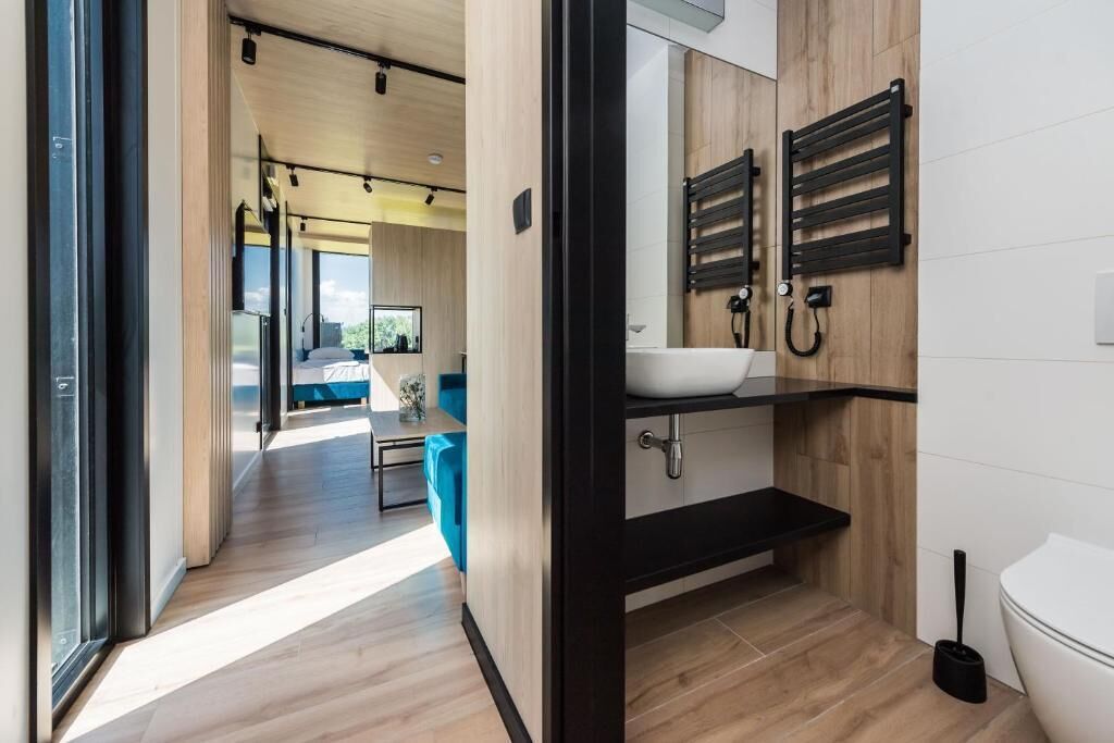 A modern bathroom with a black sink, wooden vanity, and a toilet.