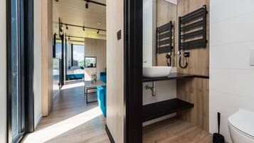 A modern bathroom with a black sink, wooden vanity, and a toilet.