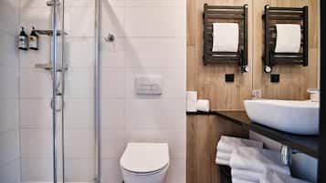 Un baño moderno con cabina de ducha de vidrio, inodoro blanco y paneles de pared de madera.