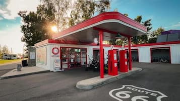 A gas station with a red canopy, fuel pumps, and a sign indicating Route 66.