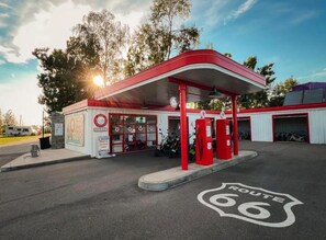 A gas station with a red canopy, fuel pumps, and a sign indicating Route 66.