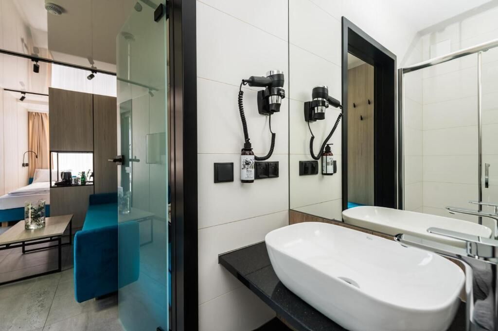 Un baño moderno con un lavamanos grande de color blanco, mampara de ducha de vidrio y un espejo con marco negro.