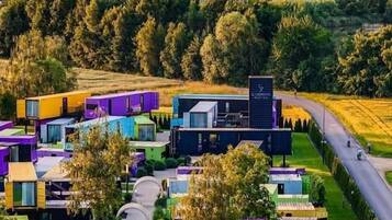 Un moderno complejo hotelero con varios edificios de colores, un patio central y una vista de una montaña rusa al fondo.