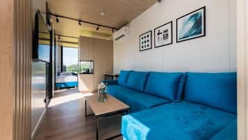 Un intérieur moderne avec un canapé bleu, une table en bois et un lit donnant sur une vue agréable.