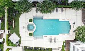 An aerial view of a swimming pool area with a sun lounger, a small deck, and a covered seating area. - Landing | Modern 2BD, Pool, Yoga Studio (Houston)