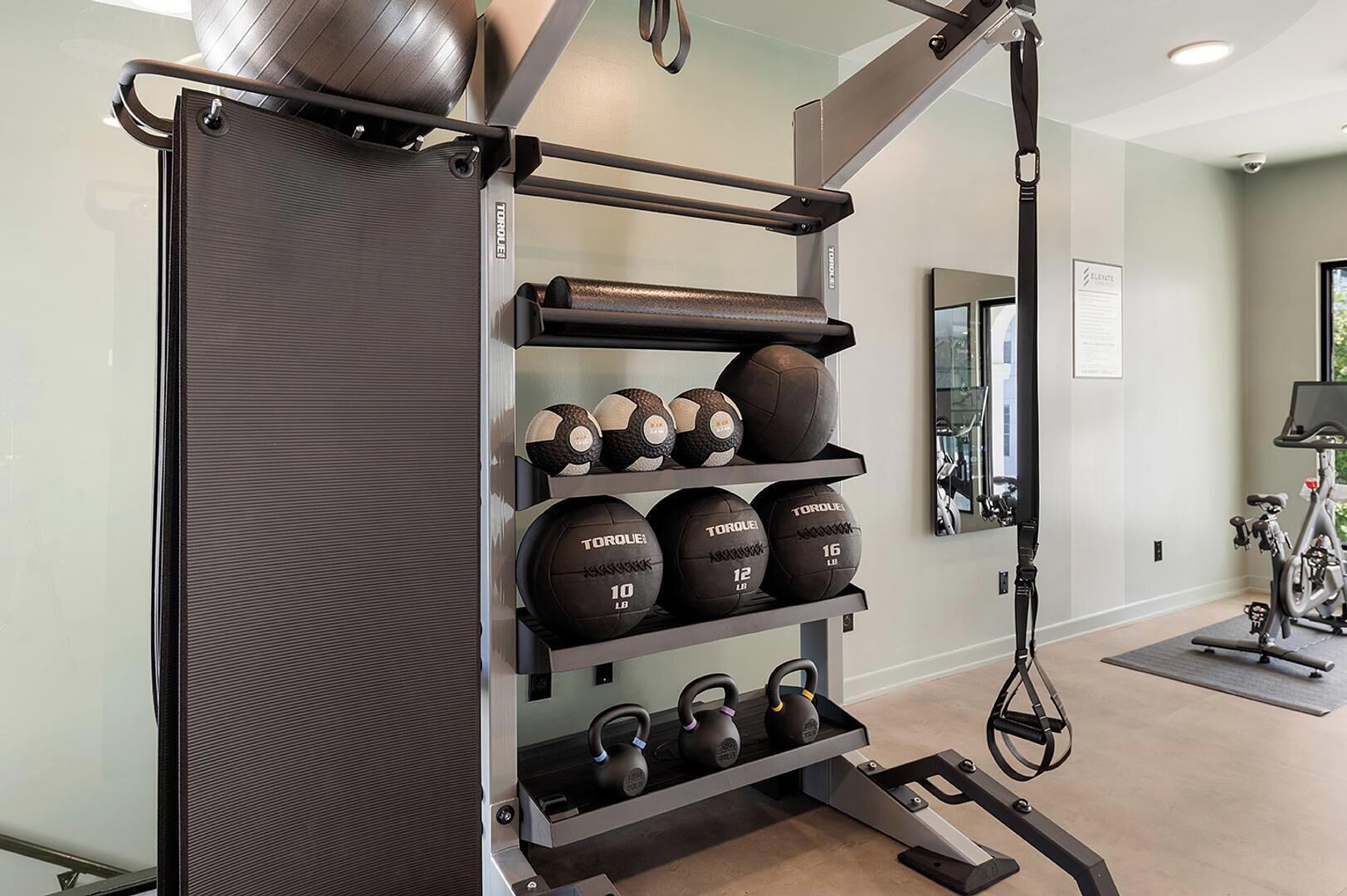 Un gimnasio en casa con un estante para pesas que contiene mancuernas y kettlebells.