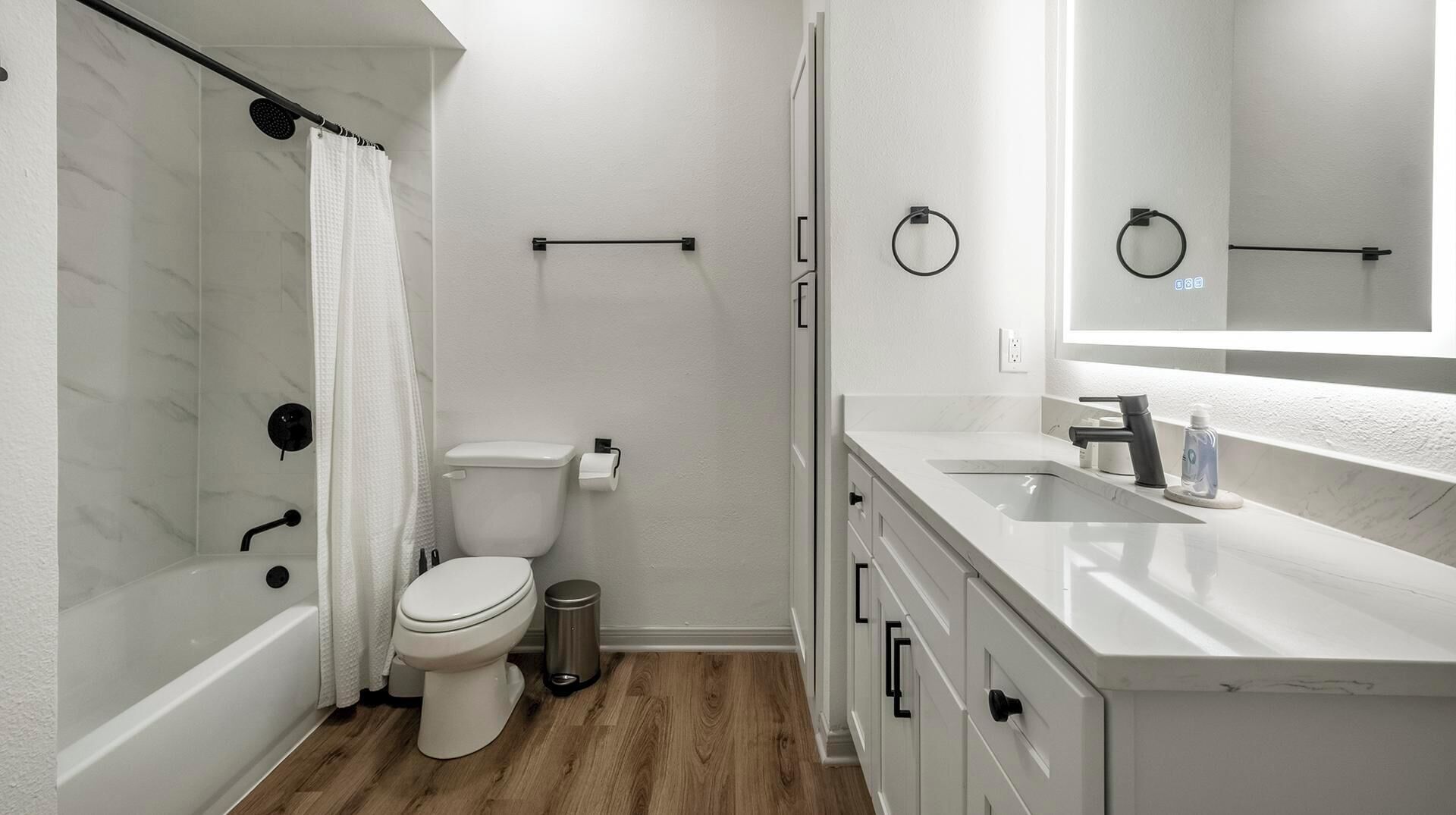 Een moderne badkamer met douche, toilet en wastafel.