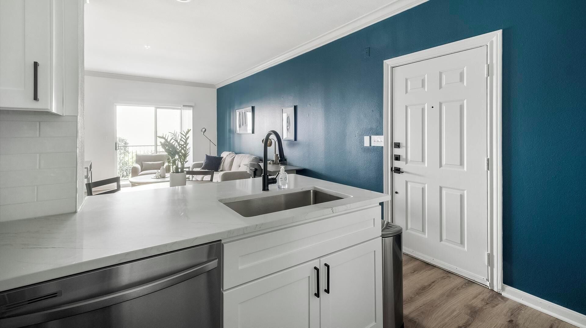 A modern kitchen with white cabinetry, a stainless steel dishwasher, and a sink.