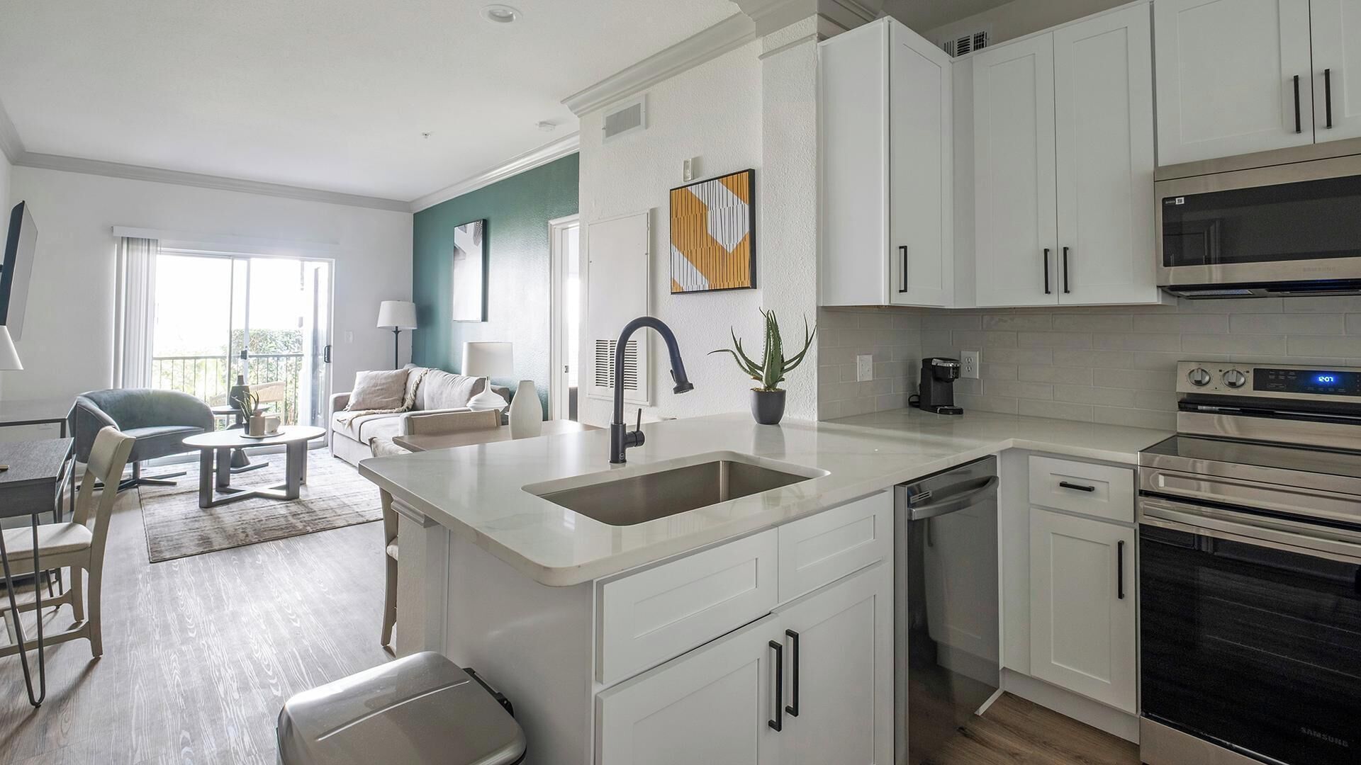 A modern kitchen with white cabinetry, a built-in dishwasher, and a stainless steel oven.