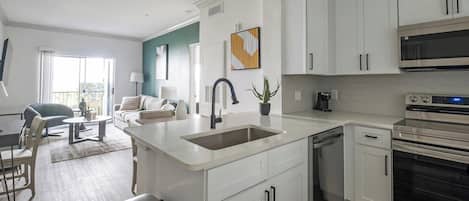 A modern kitchen with white cabinetry, a built-in dishwasher, and a stainless steel oven.