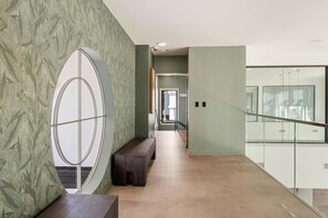 Um corredor moderno com um banco, um espelho grande e um parapeito de vidro.