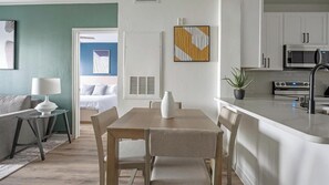 Eine moderne Küche mit Mikrowelle, Herd und Spüle. Es gibt einen Essbereich mit Tisch und Stühlen.