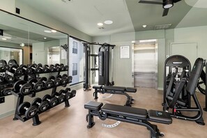 A gym with weightlifting equipment, a bench, and a mirrored wall. - Landing | Stylish 2BD, Yoga Studio, Clubhouse (Houston)