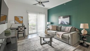 A modern living room with a sofa, coffee table, and a ceiling fan. - Landing | Modern 1BD, Clubhouse, Gym (Austin)