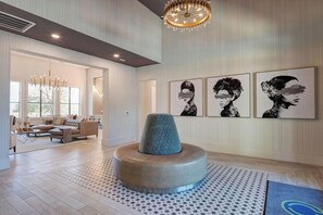 A modern interior with a round seating area, a chandelier, and wall art. - Landing | Modern 1BD, Clubhouse, Gym (Austin)