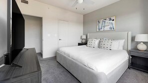 A hotel room with a bed, a television, a door, and a wall-mounted artwork. - Landing | Modern 2BD, Clubhouse, Gym (Austin)