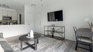 A modern living space with a kitchen, dining area, and a TV mounted on the wall. - Landing | Beautiful 1BD, Clubhouse, Gym (Austin)