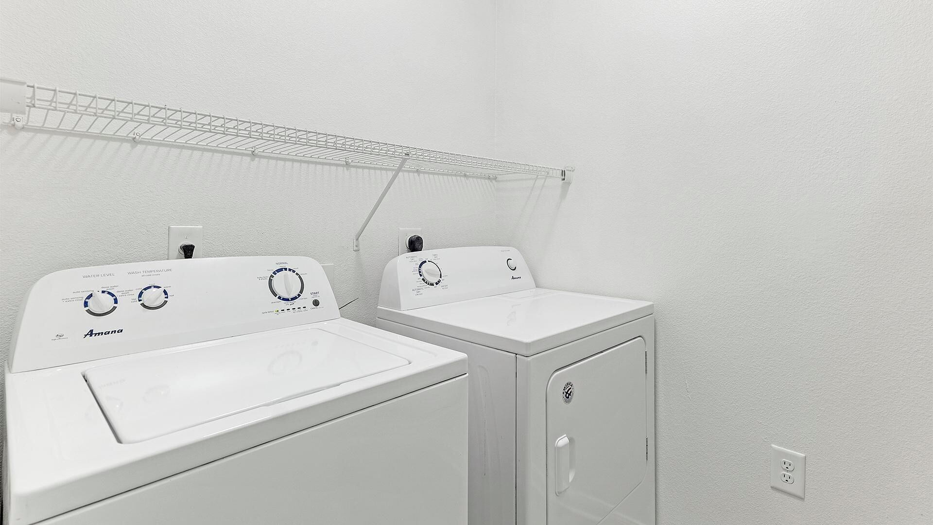 A laundry area with two white washing machines and a drying rack.