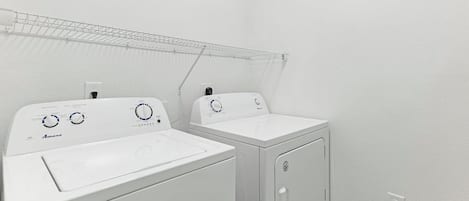 A laundry area with two white washing machines and a drying rack.