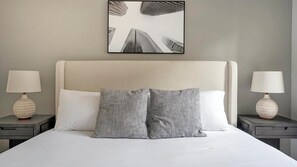 Ein Hotelzimmer mit einem großen Bett, zwei Nachttischen, zwei Lampen und einem gerahmten Bild an der Wand.